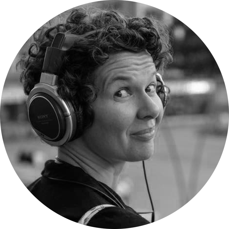 Séverine SKIERSKI - Audiodescriptrice - artisan de l’accessibilité sur des missions ponctuelles. De dos, Séverine Skierski lance un regard espiègle par-dessus son épaule. Ses cheveux sont courts et bouclés. Elle a une quarantaine d’années et un gros casque audio sur les oreilles.