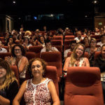 Installés dans les fauteuils rouges de la salle de cinéma, une petite centaine de personnes applaudit en souriant.