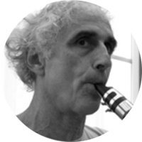 François LEBEGUE - Président de l'association Les Yeux Dits - Directeur de l’école de musique l’AMH. François Lebègue a une soixantaine d’années, les sourcils noirs et les cheveux blancs bouclés. Il souffle dans un embout de clarinette, le regard dense et concentré.